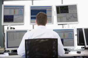 Stock Trader Looking At Multiple Monitors
